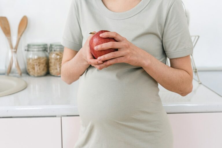 Kobieta w ciąży trzyma jabłko